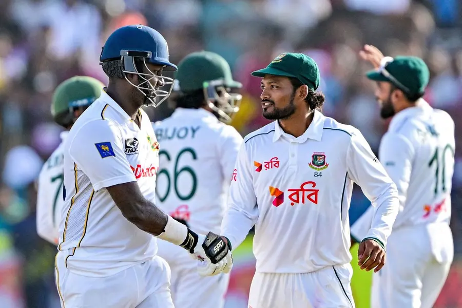 Bangladesh's captain Najmul Hossain Shanto (R) shakes hands with Sri Lanka's Angelo Mathews