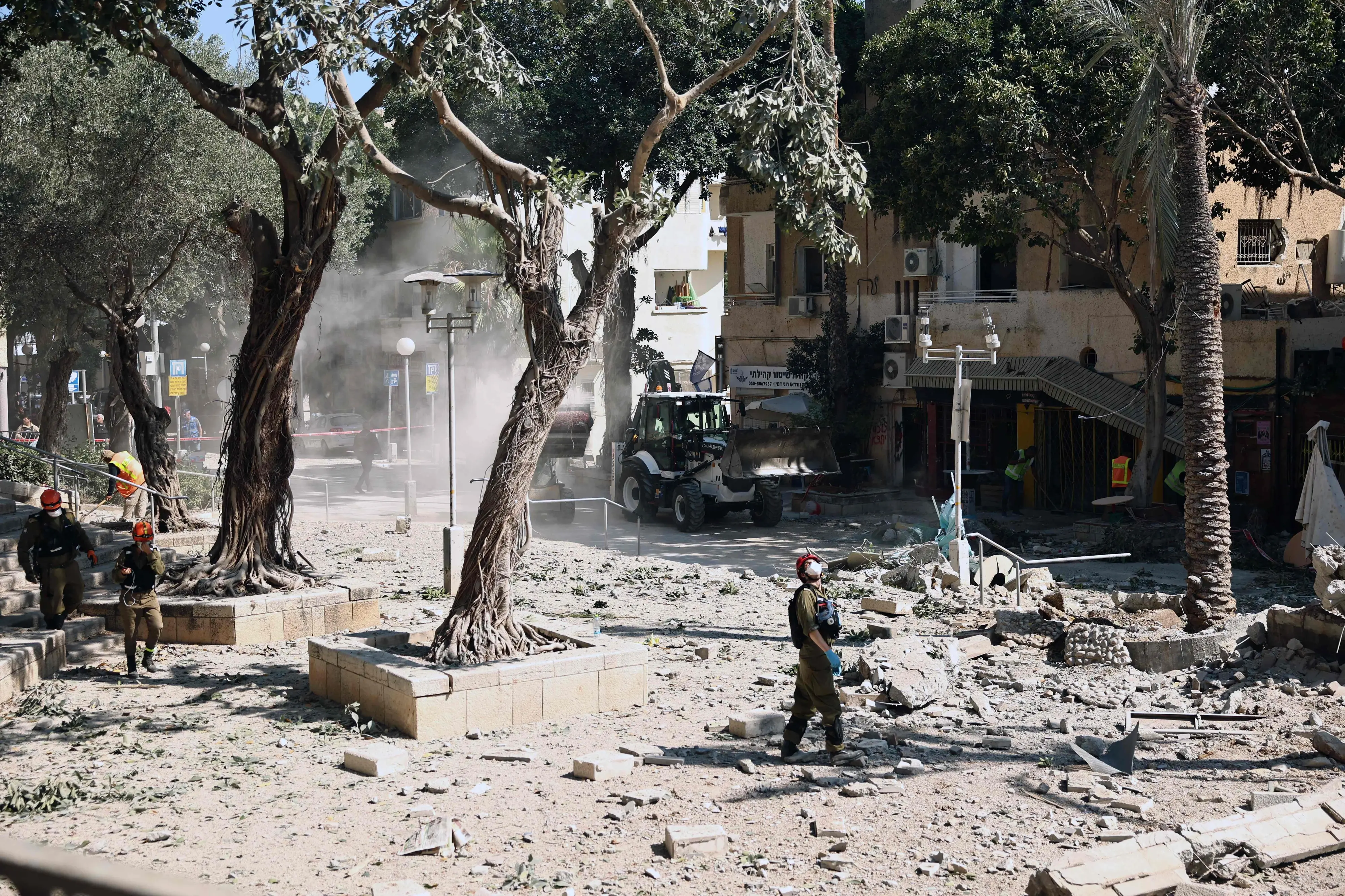 An Israeli first responder stands amid the rubble in front of a building hit during an Iranian strike in the port city of Haifa | AFP