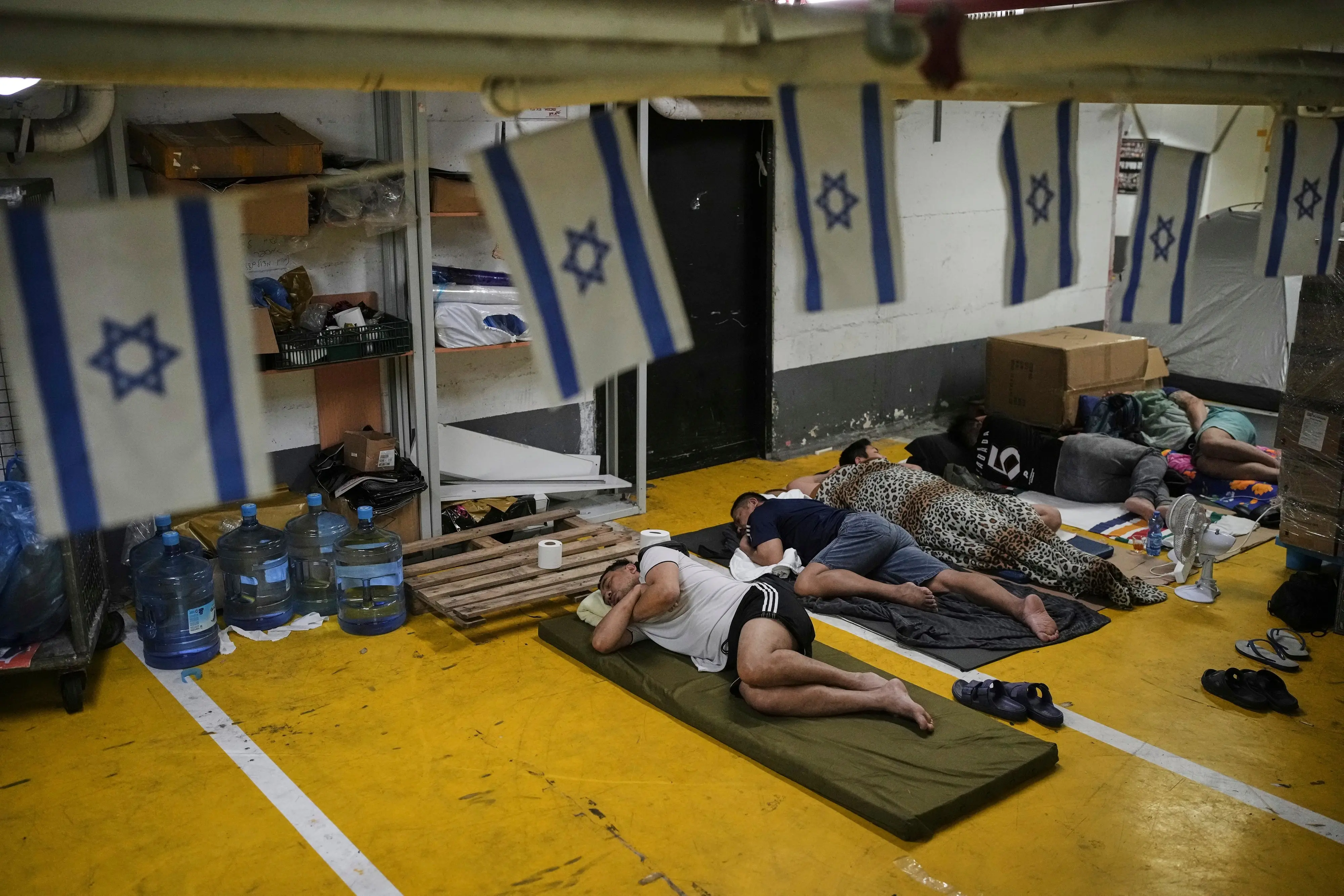 People rest in an underground parking garage used as a shelter amid fears of possible Iranian missile attacks, in Tel Aviv | PTI