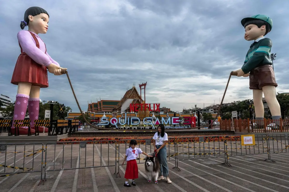 People stand infront of 12 meter-tall statues of Young-hee (L) and the newly revealed Cheol-su (R ), the iconic doll characters from the popular Netflix's South Korean TV series Squid Game | AFP