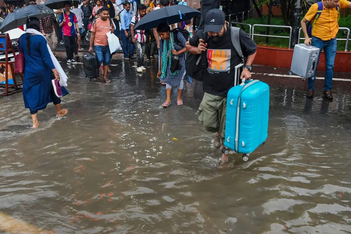 Passengers on their way towards the railway platform walk through the waterlogged premises of Ranchi railway station (Photo: PTI)