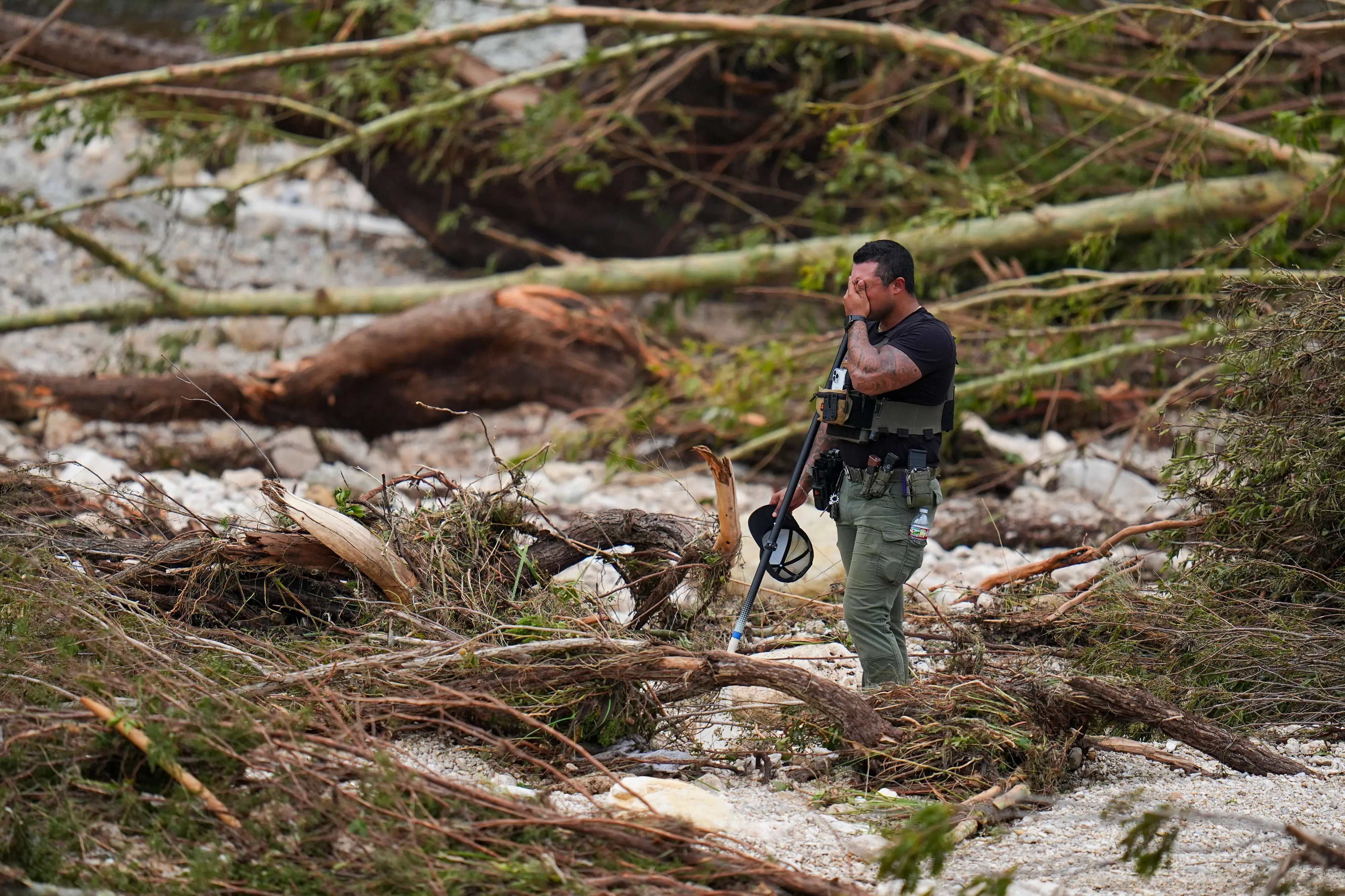 A Sheriff's deputy pauses while combing through the banks of the Guadalupe River near Camp Mystic after a flash flood swept through the. | Photo: AP