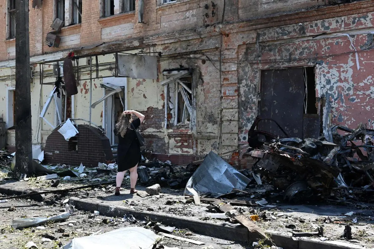 A woman stands among debris next to a recruitment centre building damaged after a drone attack in Kharkiv | Photo: AFP