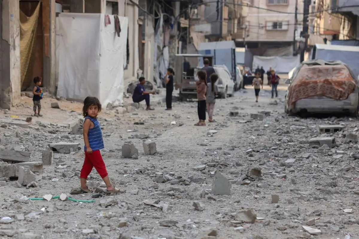 File Photo: Palestinian children stand on a street covered in the rubble of a building | AFP