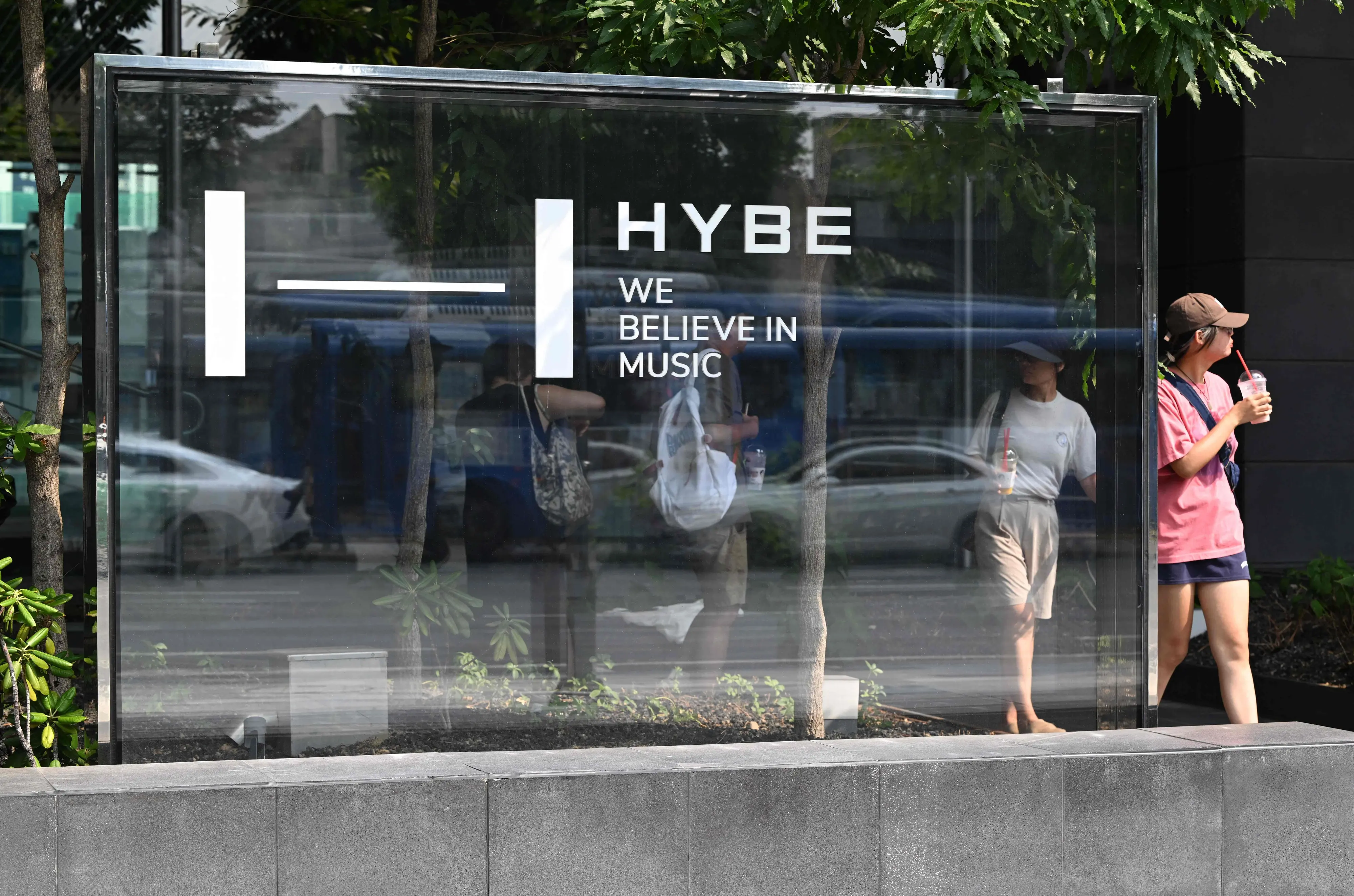 Pedestrians walk past the signage for HYBE, the agency behind K-pop megastars | Photo: AFP