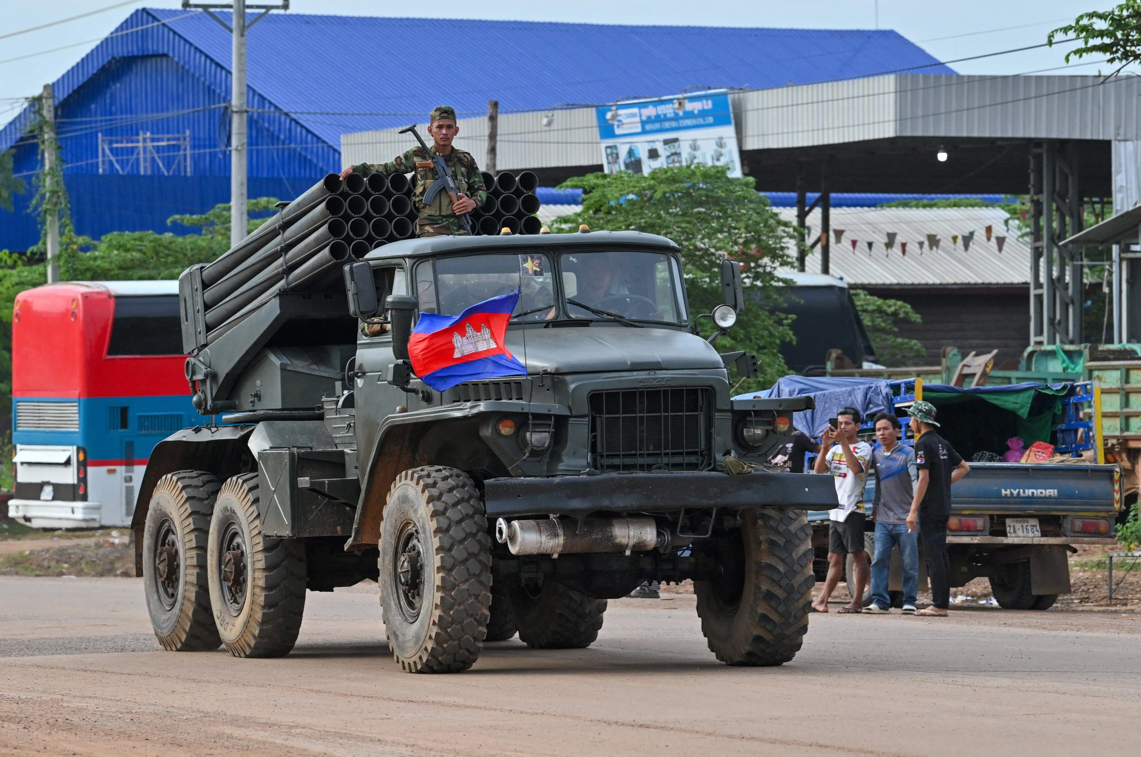 A Cambodian soldier stands on a truck carrying a Russian-made BM-21 rocket launcher travelling along a street in Oddar Meanchey province | AFP