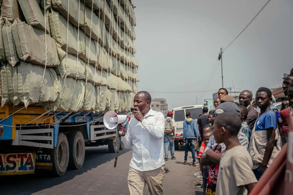 The neighbourhood chief, who helped the government gather the population, returns with a megaphone to ask everyone to leave and clear the road as the meeting has ended in Goma on July 24, 2025 (Photo: AFP)
