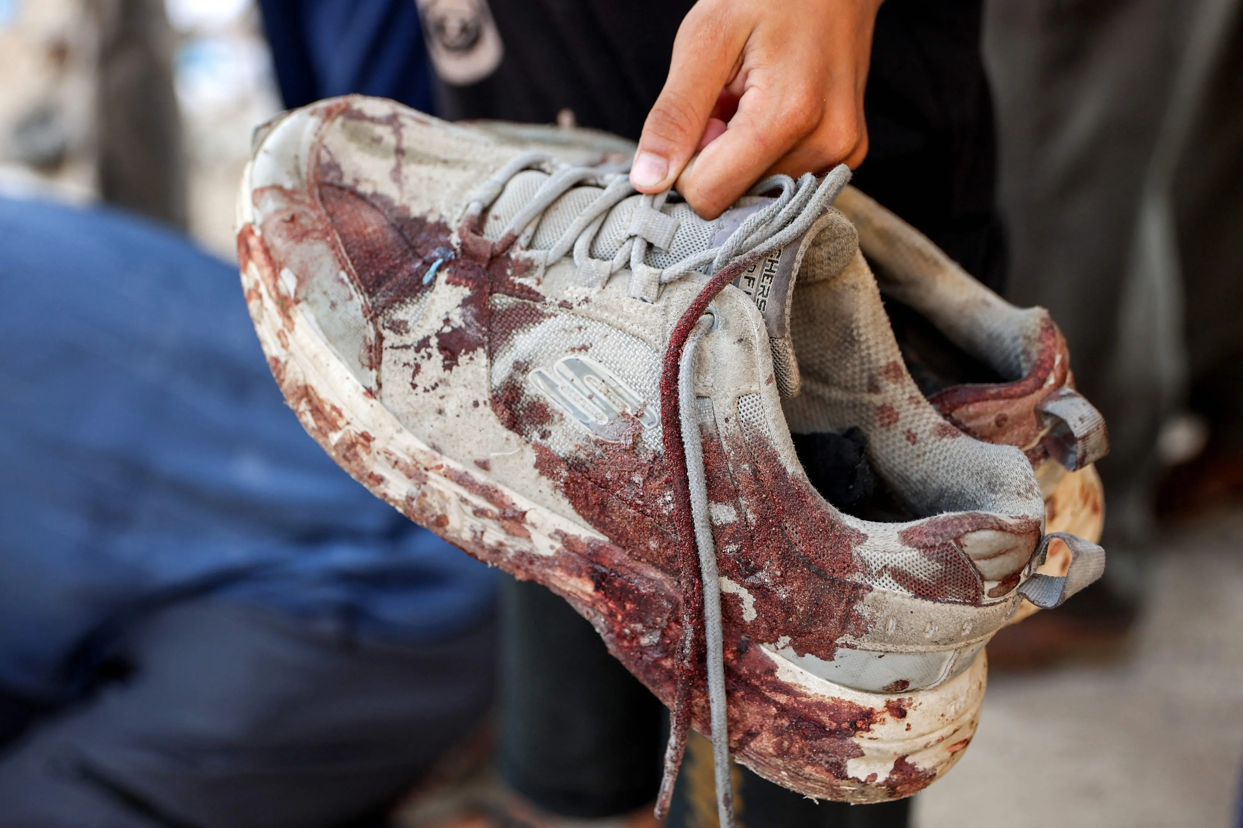 A person holds the bloodied shoes of young man who was killed by gunfire while waiting for aid trucks entering the northern Gaza Strip | Photo: AFP