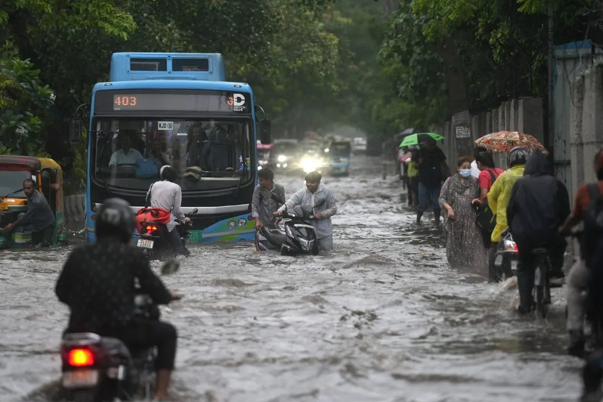 Commuters wade through a waterlogged road amid heavy rainfall, in New Delhi, Thursday, Aug. 14, 2025 (Photo: PTI)