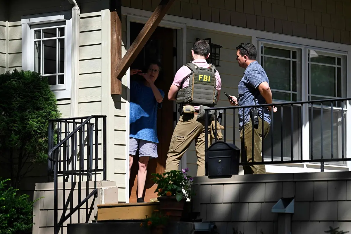 Members of the Federal Bureau of Investigation (FBI) speak to a resident following a mass shooting at Annunciation Catholic Church | Photo: AFP