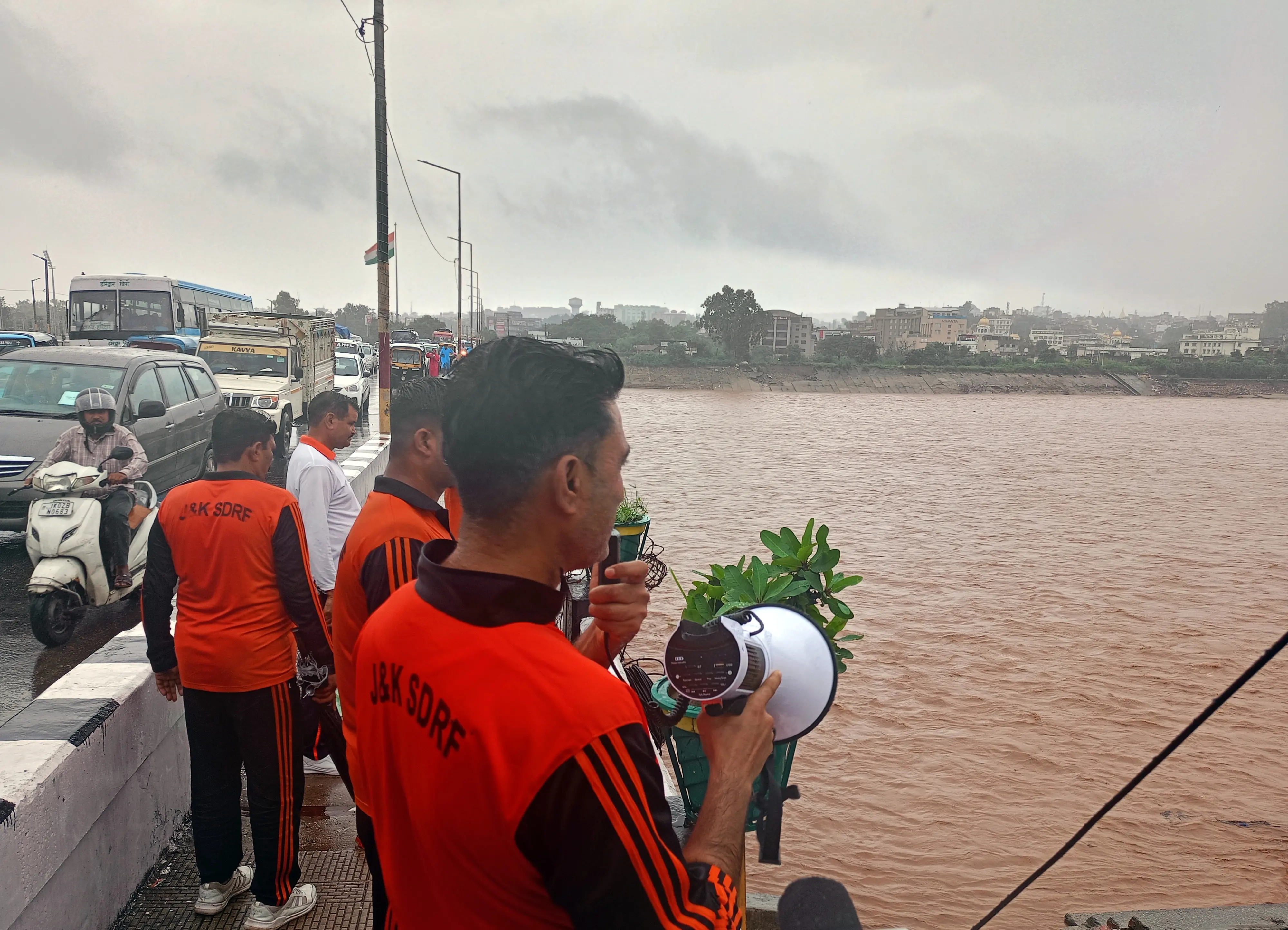 An SDRF personnel announces to vacate the surrounding area as the water levels of the Tawi River rise