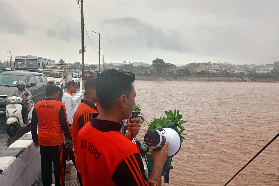 An SDRF personnel announces to vacate the surrounding area as the water levels of the Tawi River rise