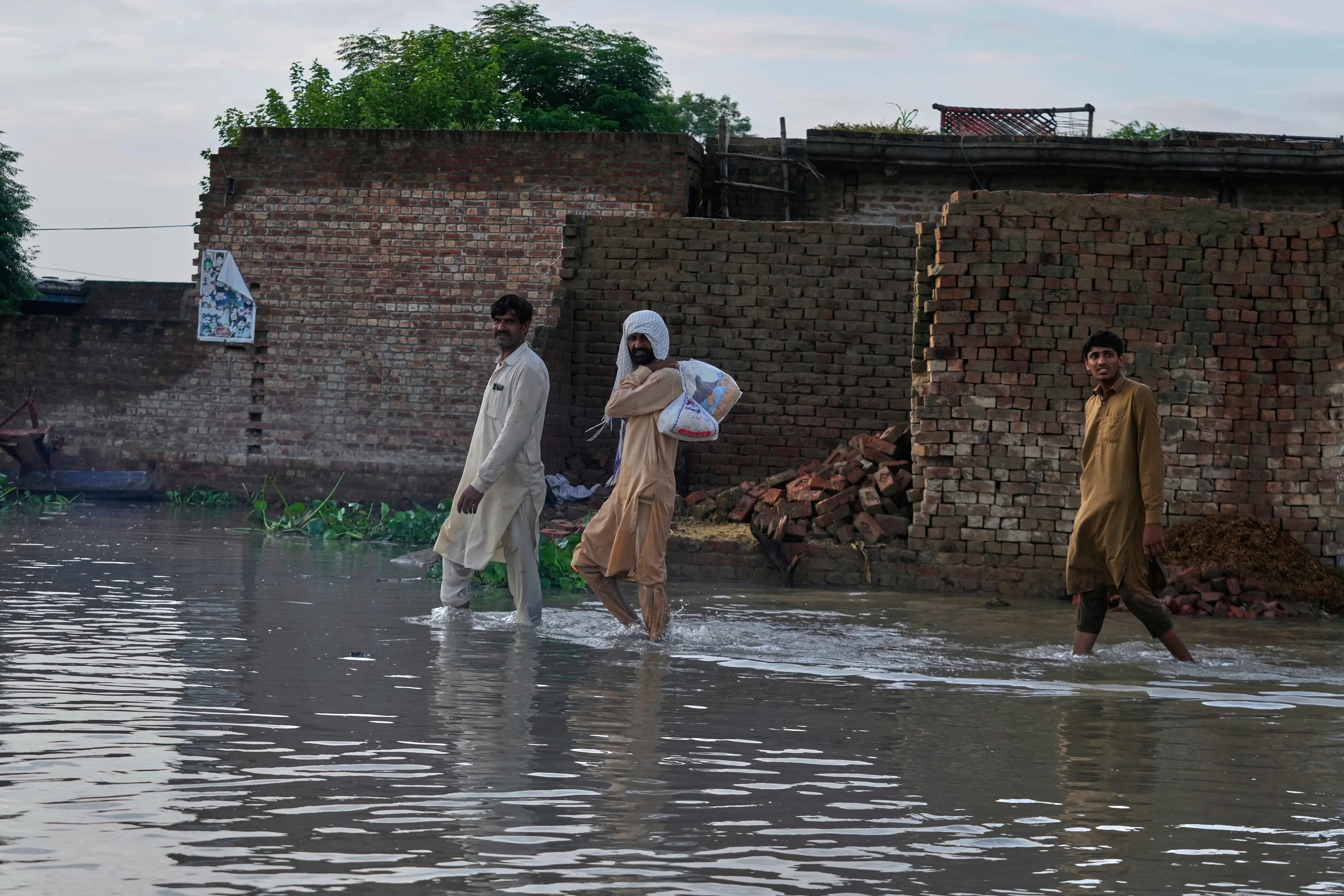 Villagers walk through a flooded area | Photo: AP