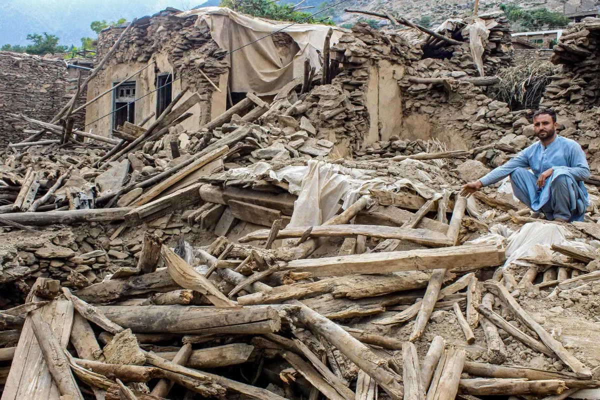 File Photo: An Afghan man sits amid the remains of a damaged house, in the aftermath of an earthquake at the Dara-i-Nur district of Nangarhar province | AFP