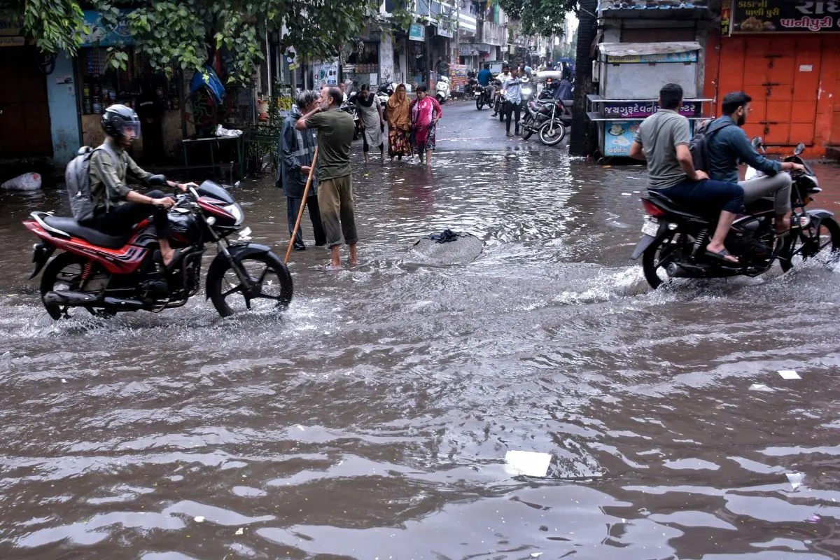 Commuters make their way through a waterlogged road during heavy rainfall, in Surat on Friday. (ANI Photo)