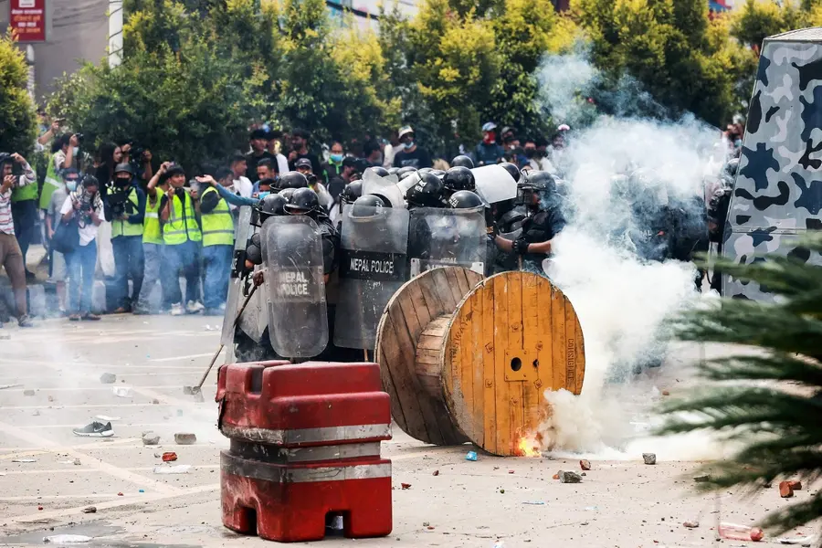 Riot police personnel fire tear gas as demonstrators pelt stones during a protest outside the Parliament in Kathmandu