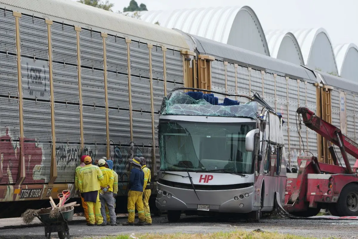 Workers stand at the site of an accident where a freight train crashed into a double-deck bus in Atlacomulco, Mexico (Photo: AP)
