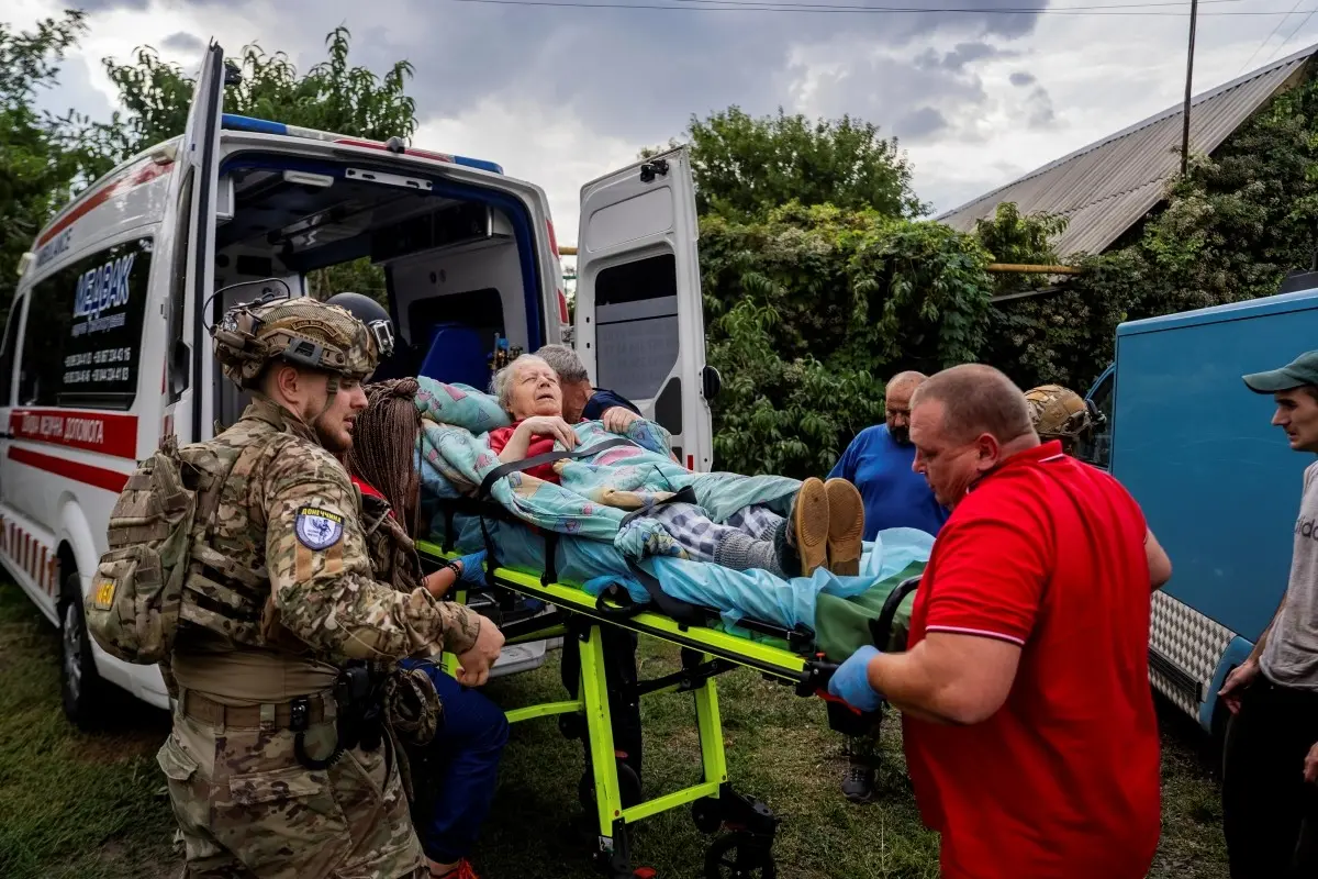 Policemen and medics transfer to the ambulance Olha Trush, 86 from the village of Yarova, that was hit by Russian aerial strike, which killed dozens of civilians | Photo credit- AP