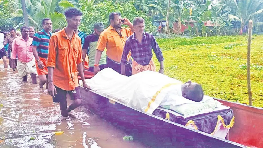 ഓമനക്കുട്ടന്റെ മൃതദേഹം വെള്ളംകയറിയ നടവഴിയിലൂടെ വള്ളത്തില്‍ വീട്ടിലെത്തിക്കുന്നു