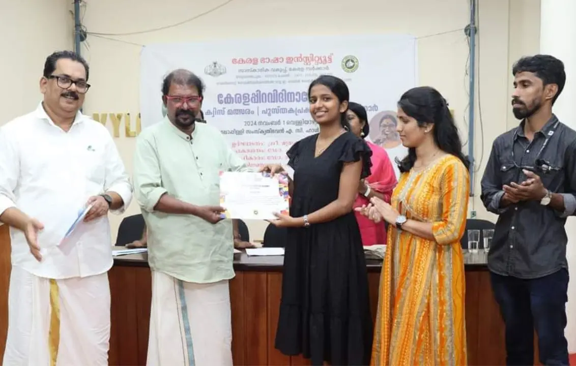 വിജയികളായ അശ്വിതി പി.എ., ഗീതിക വി.കെ. എന്നിവര് മലയാളം മിഷന് ഡയറക്ടര് കവി മുരുകന് കാട്ടാക്കടയില്നിന്നും സമ്മാനം ഏറ്റുവാങ്ങുന്നു