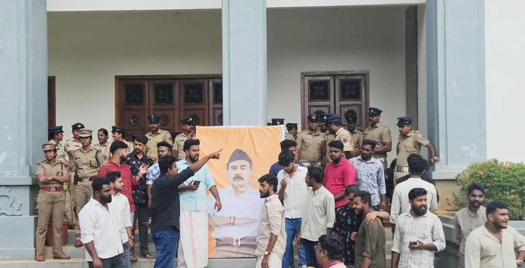 കേരള യൂണിവേഴ്സിറ്റി വൈസ് ചാൻസിലർ മോഹനൻ കുന്നുമ്മലിനെ ആർഎസ്എസ് വേഷം ധരിപ്പിച്ച ചിത്രം യൂണിവേഴ്സിറ്റിയുടെ പ്രധാന കവാടത്തിനു മുൻപിൽ സ്ഥാപിച്ചപ്പോൾ |ഫോട്ടോ: അജ്മൽ എൻ.എസ്.