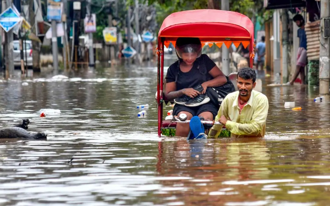 അസമില് കനത്ത മഴയെത്തുടര്ന്ന് വെള്ളക്കെട്ടായ റോഡിലൂടെ ഒരാള് റിക്ഷ വലിക്കുന്നു | PTI