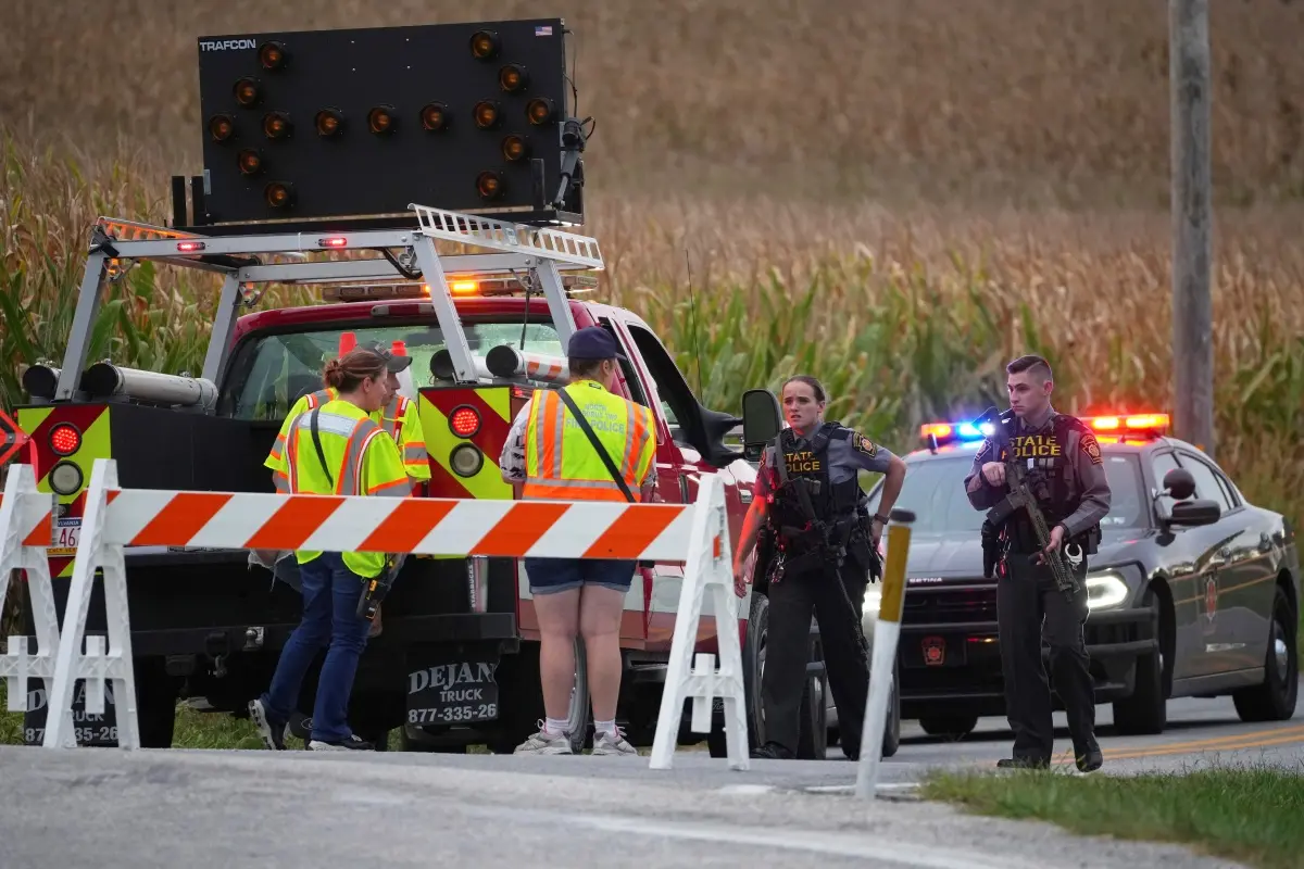 Pennsylvania state police troopers and emergency workers block a road after multiple police officers were shot and killed on Wednesday, in North Codorus, Pa. | Photo: AP