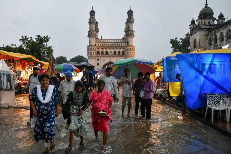 People wade through water after a heavy downpour at Chaar Minar