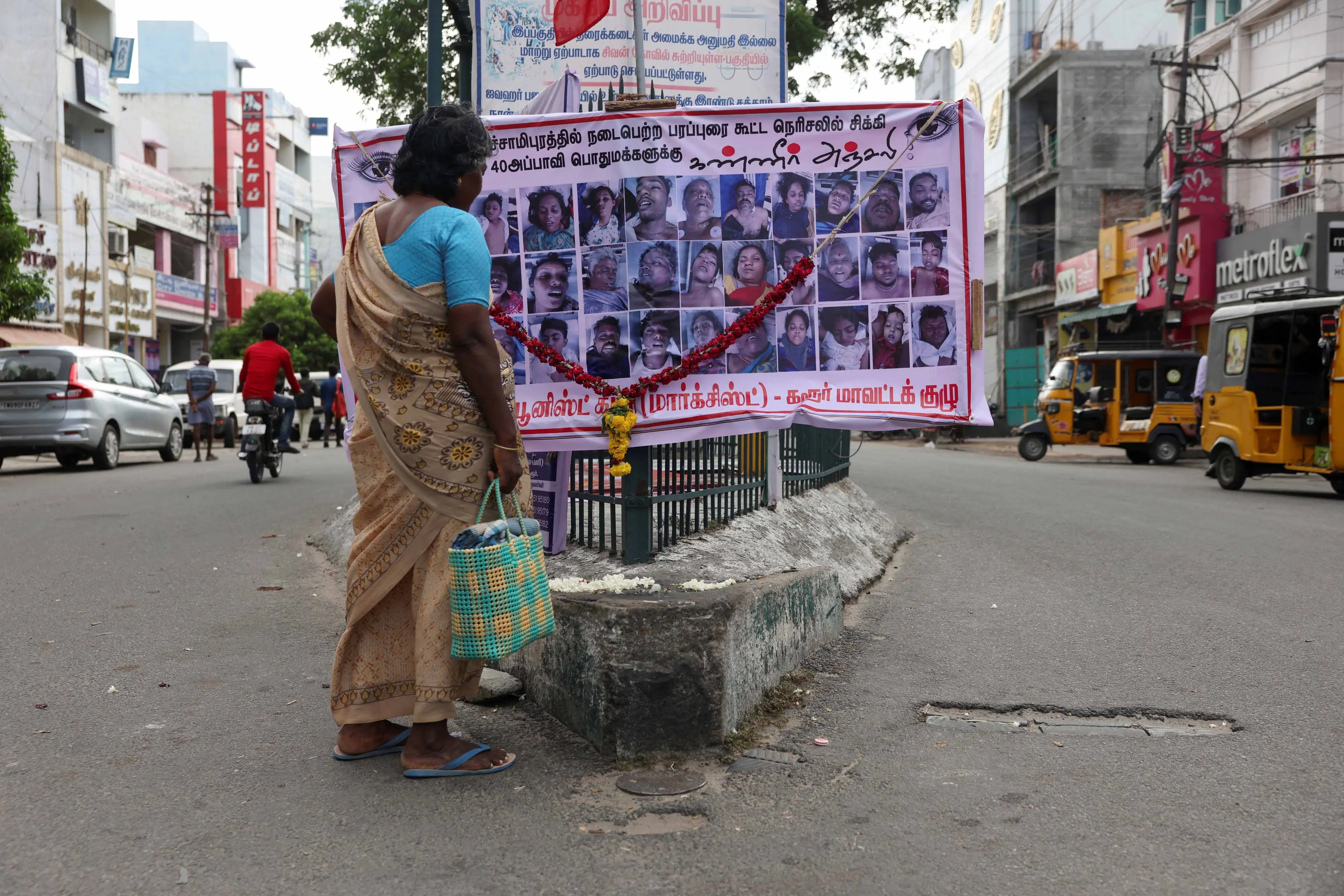 A woman looks at a poster showing the faces of people who died in a stampede during an election campaign rally held by the Tamilaga Vettri Kazhagam party, in Karur on Monday. | Photo:ANI