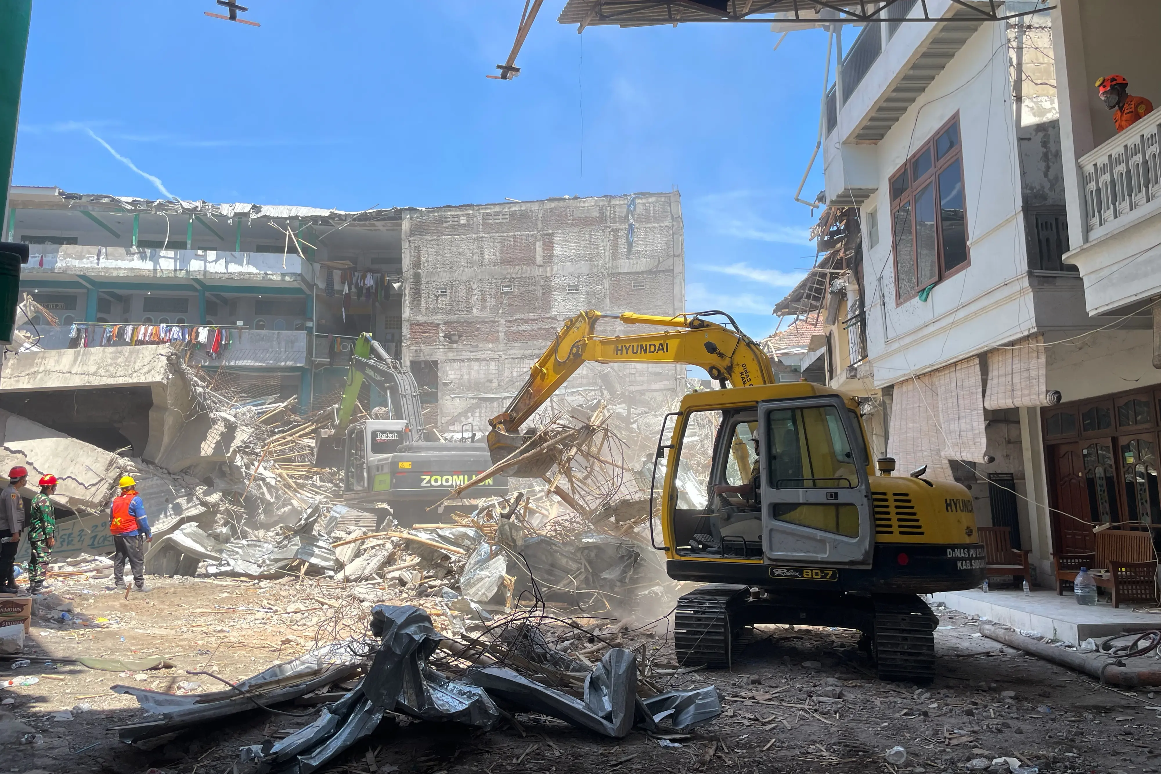 Rescuers use heavy machines to clear up the rubble of a building that collapsed at an Islamic boarding school during the search for victims in Sidoarjo, East Java, Indonesia | Photo: AP