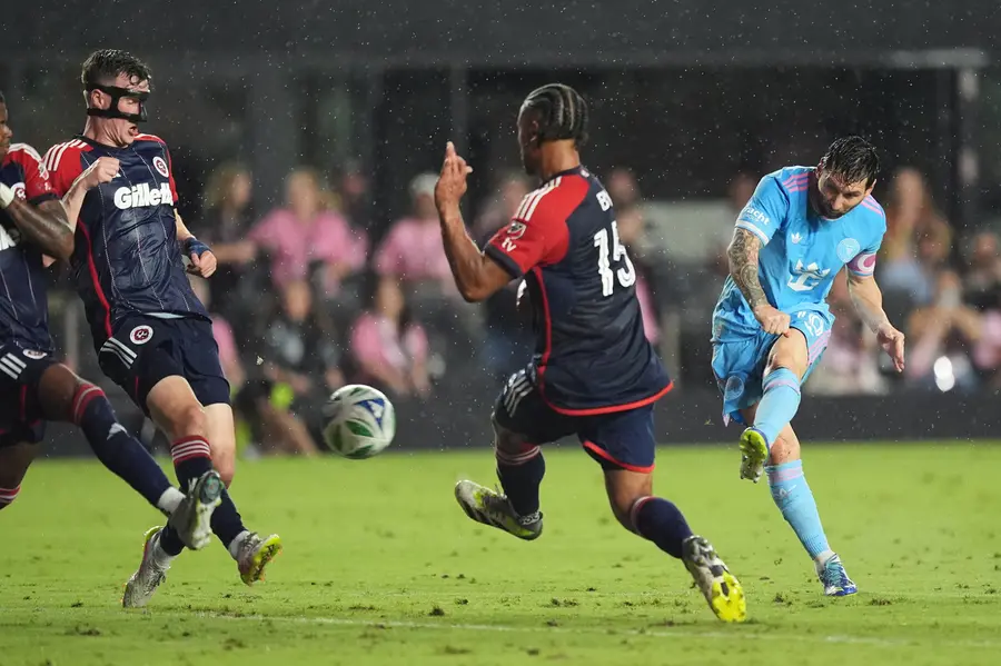 Lionel Messi takes a shot past New England Revolution defender Tanner Beason (4), second left, and midfielder Brandon Bye (15) during the first half of an MLS soccer match