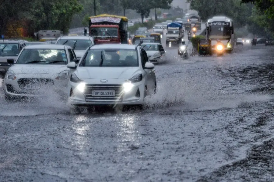 Commuters wade through heavy rain and waterlogged road at ITO in New Delhi. (ANI Photo)