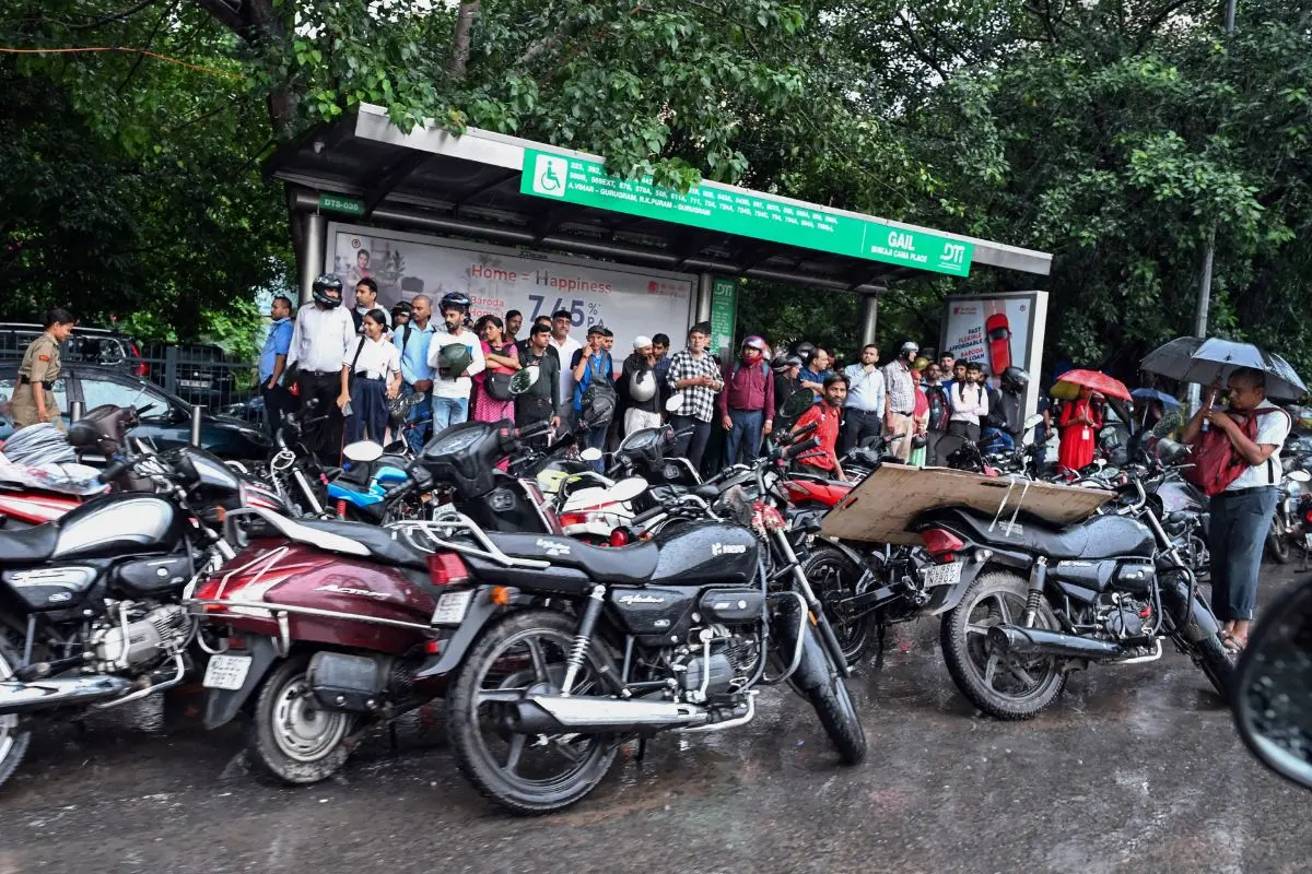 Commuters take shelter under the Bhikaji Cama Place bus stop amid rain, in New Delhi on Tuesday (Photo: ANI)