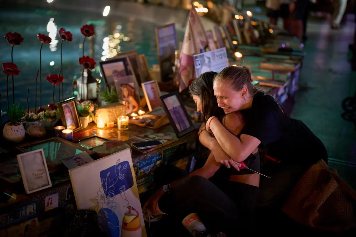 Yuval Miranda and Katya Emelianova cry as they embrace next to the photographs of Israelis who were killed in the deadly Oct. 7, 2023 Hamas attack on Israel, at a memorial marking the two year anniversary of the assault, in Tel Aviv, Israel. | Photo: AP