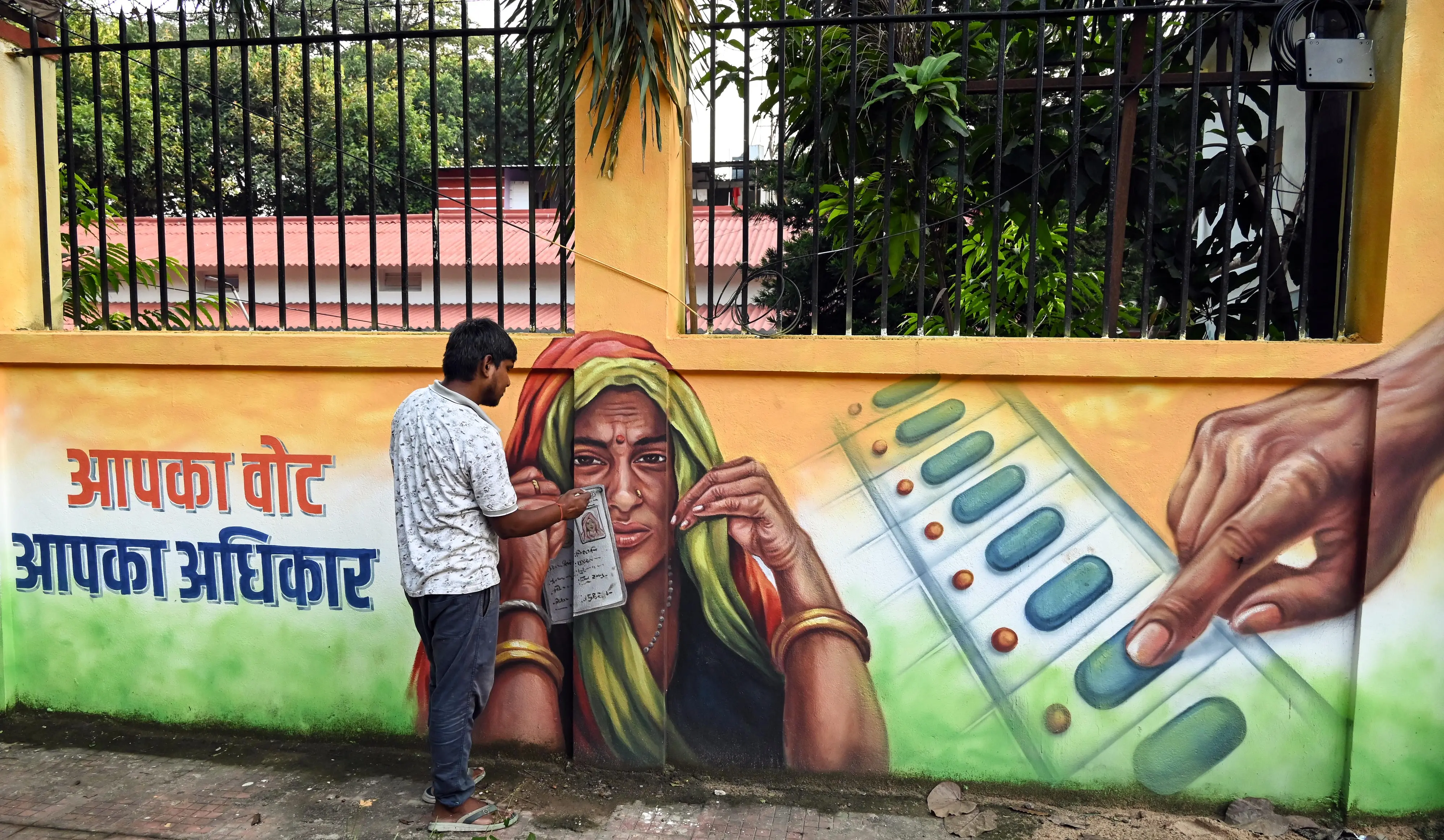 An artist gives final touches to a voter awareness mural on the wall, in Patna on Wednesday. | Photo: ANI