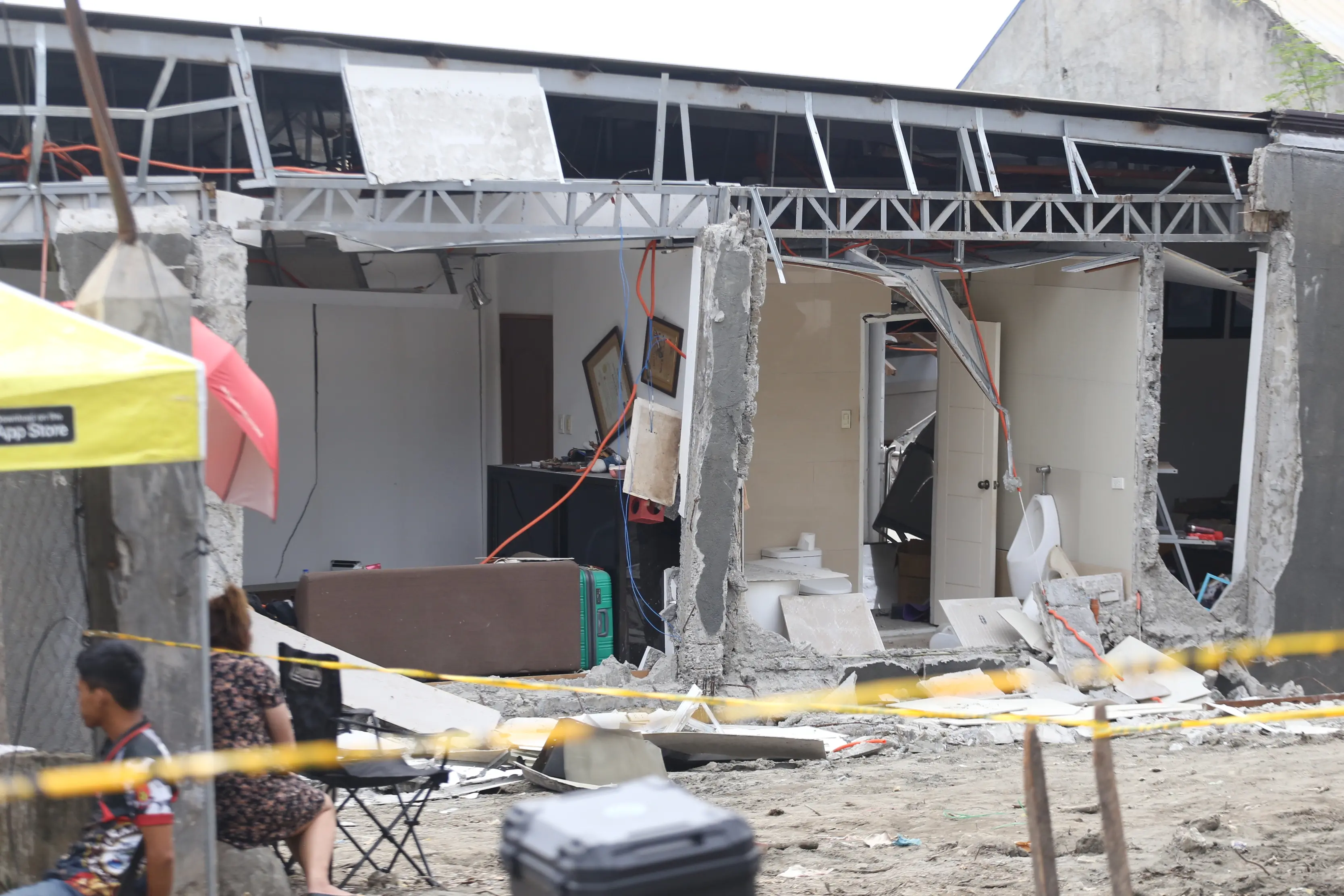 Residents stay beside a damaged house after a strong earthquake in Davao City, southern Philippines. | Photo: AP