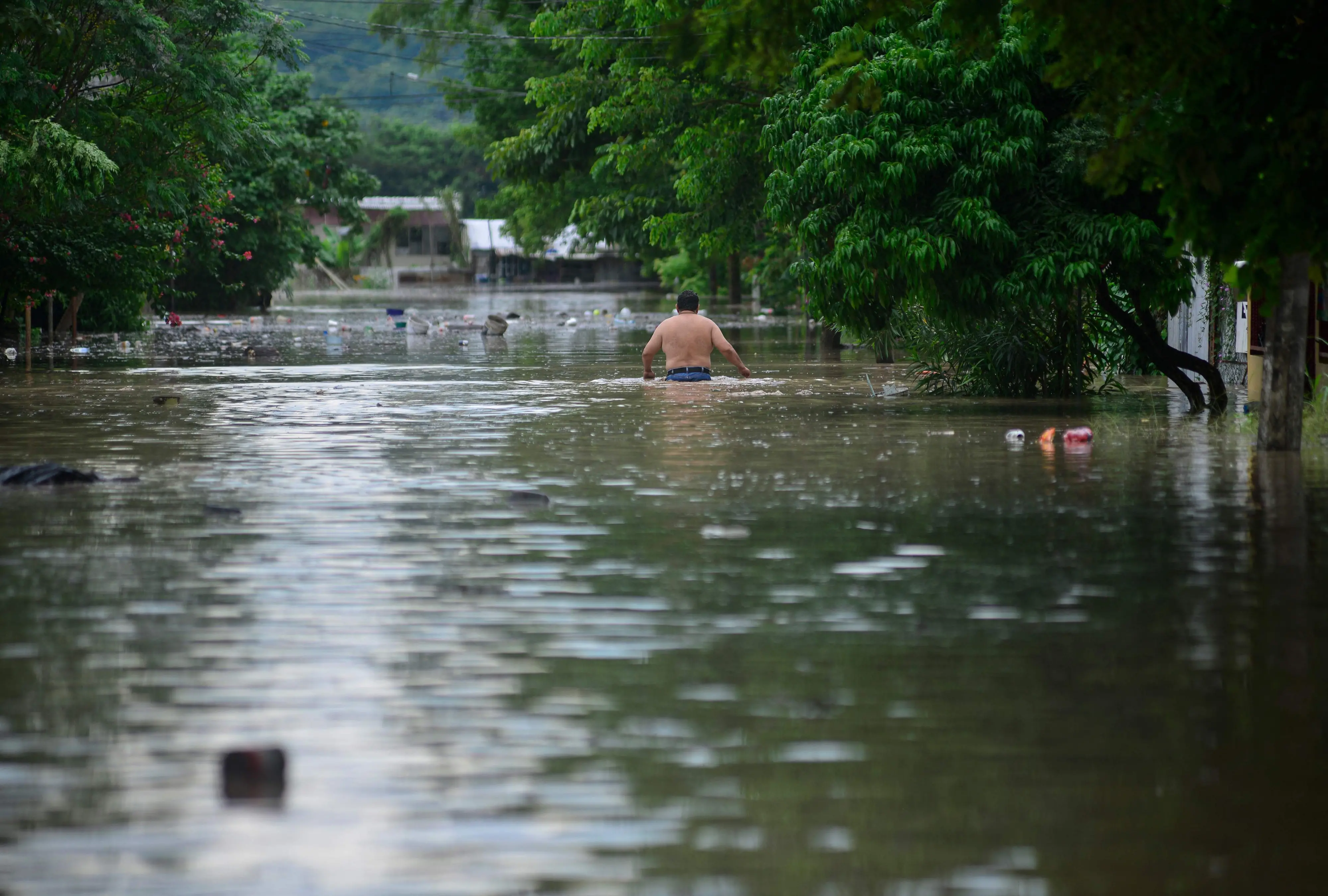 A man wades through a flooded street after heavy rains in Poza Rica, Veracruz state, Mexico | Photo: AFP