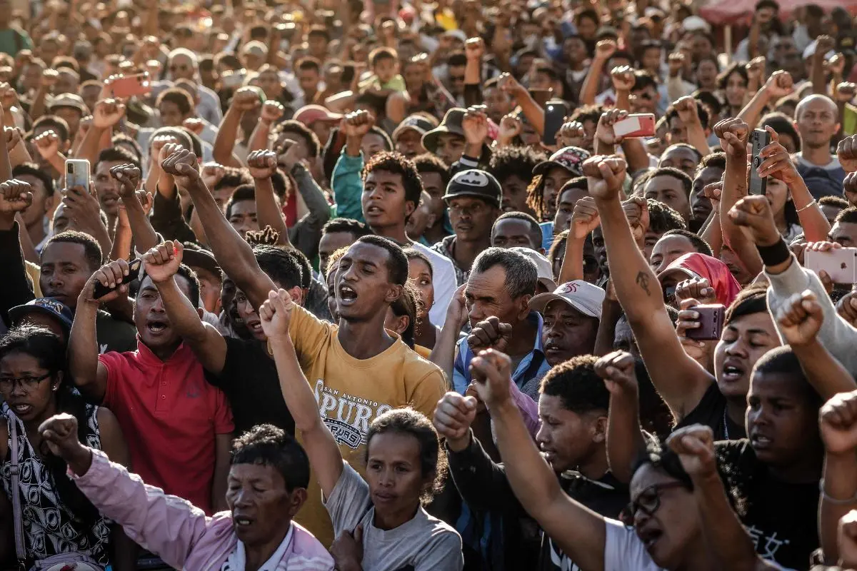 Residents and protesters chant national songs and raise their fists as they gather for a civil society rally demanding the resignation of President Andry Rajoelina and paying tribute to the victims of the protests in Antananarivo, on October 13, 2025. (Photo by Luis TATO / AFP)