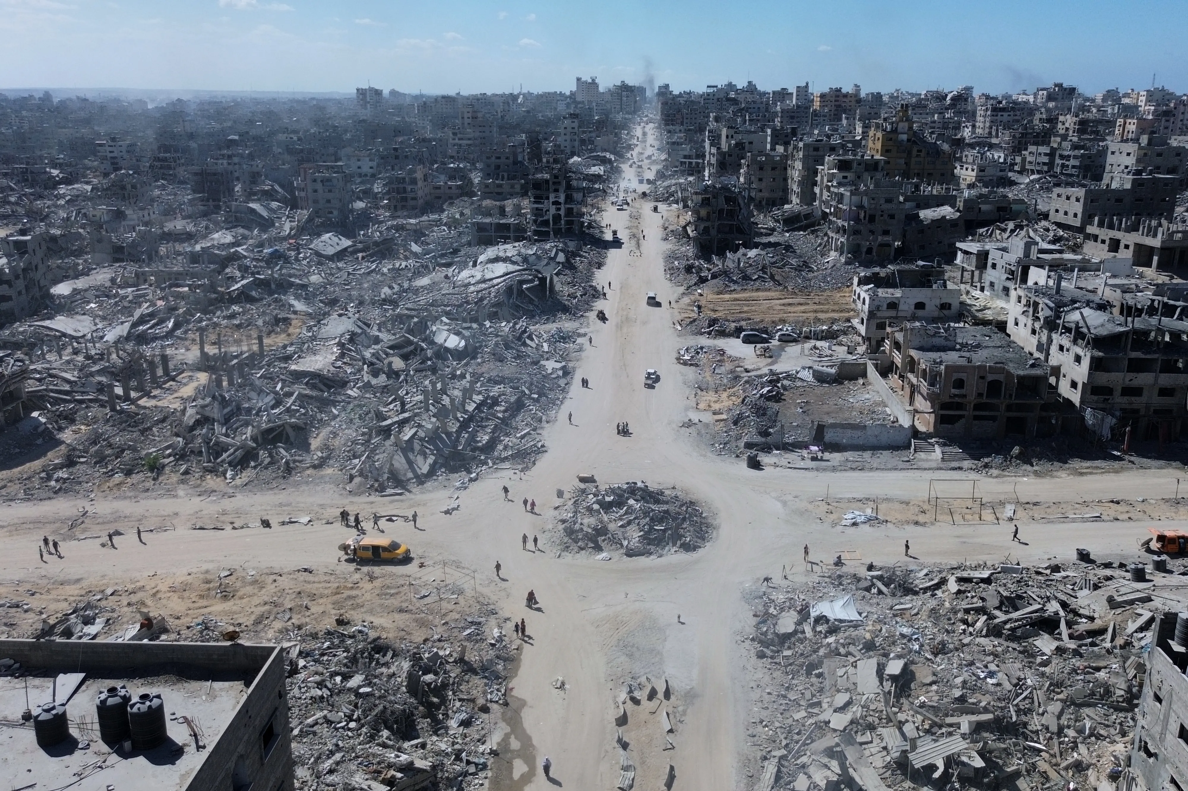 In this drone photo, Palestinians walk in an intersection surrounded by buildings destroyed during two years of Israeli army bombardments in Gaza City | AP