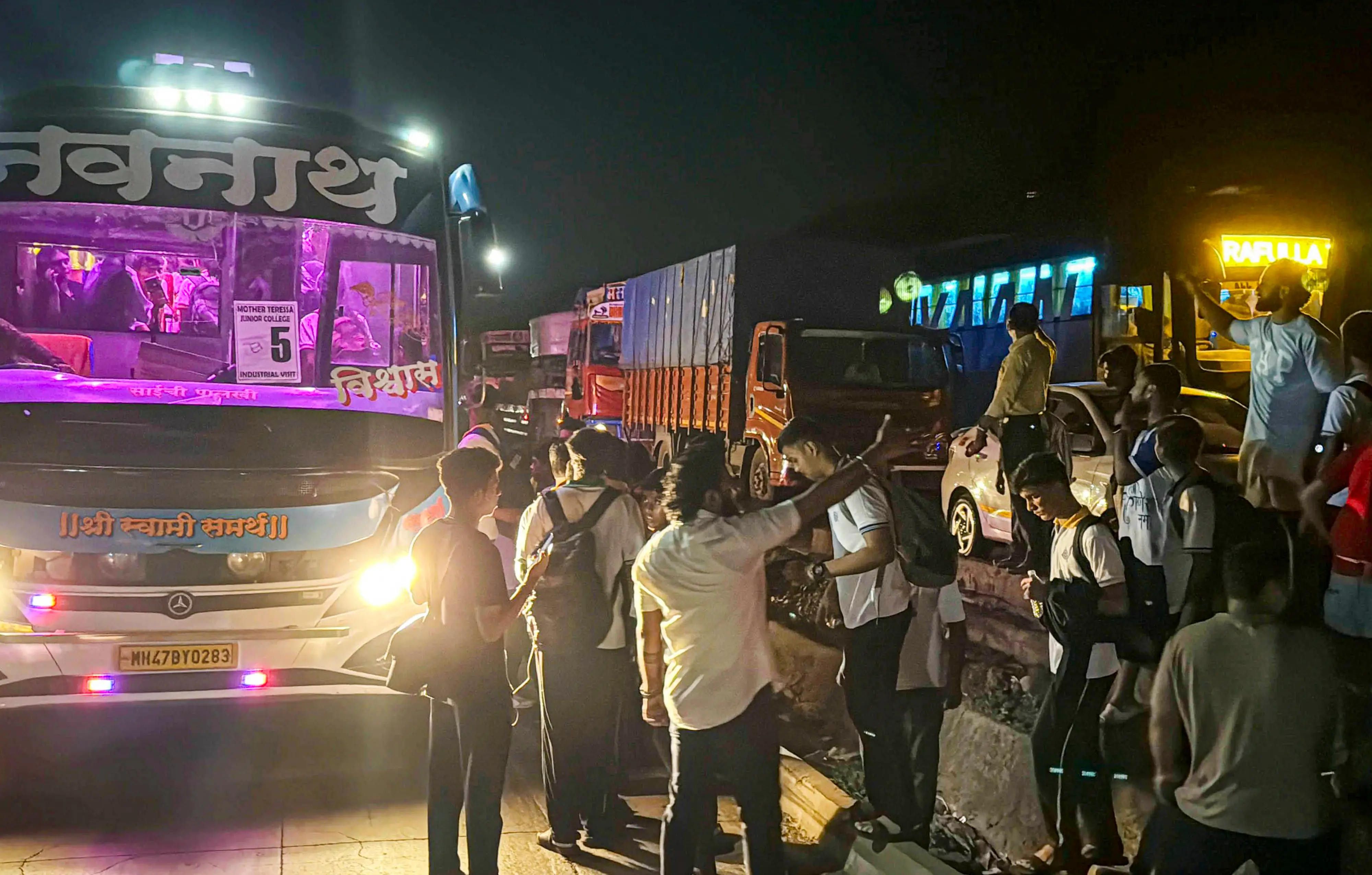 Stranded students stand near a pavement amid a traffic jam on the Mumbai-Ahmedabad National Highway at Vasai, in Palghar district | Photo: PTI