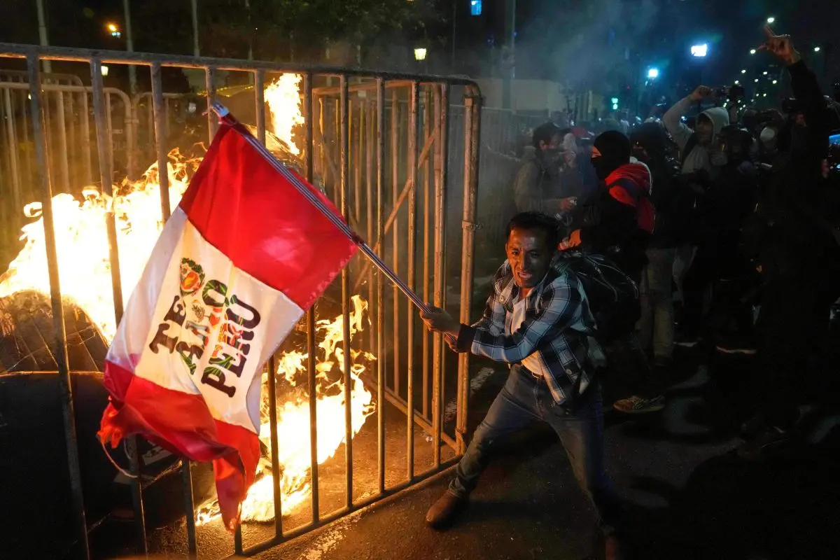 A demonstrator waves a Peruvian flag as a cardboard doll burns in front of Congress during a protest against the newly installed President Jose Jeri in Lima, Peru. Photograph: AP Photo/Martin Mejia