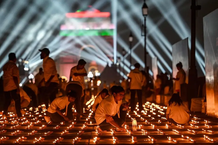People light diyas, or traditional earthen oil lamps, as a drone laser show is organised at the India Gate memorial as part of the Diwali celebration
