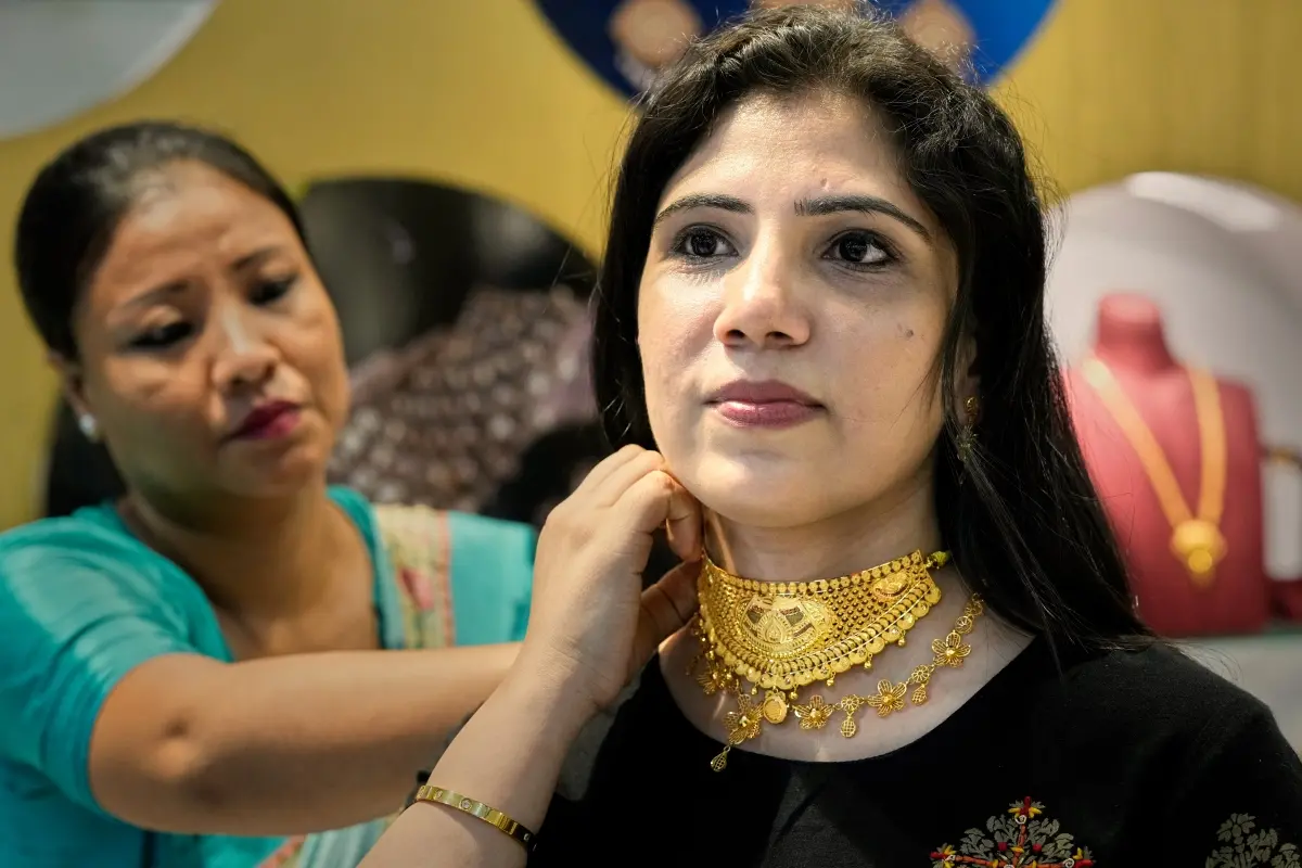 A saleswoman shows a gold necklace to a customer on Dhanteras