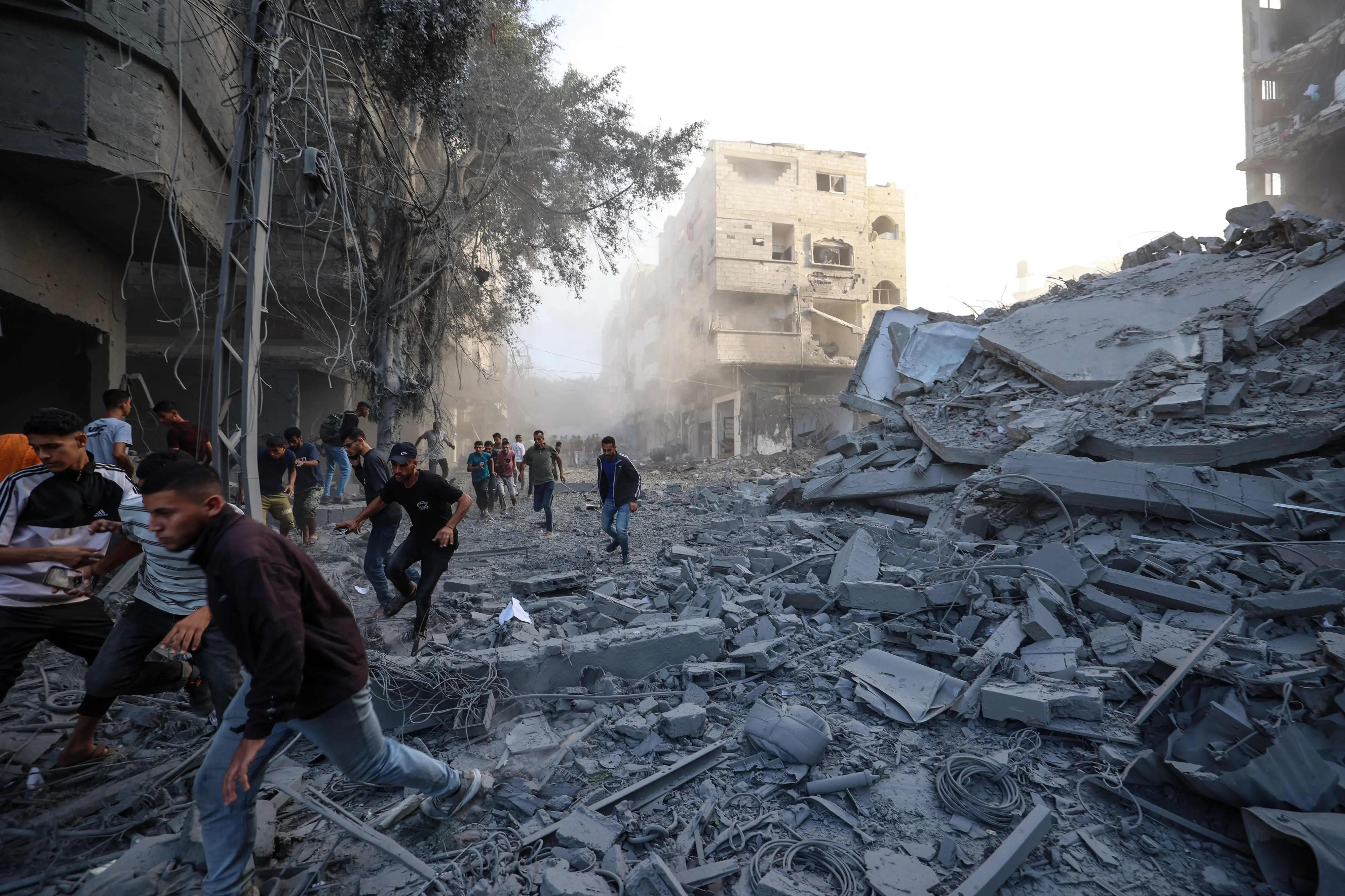 People run for cover following an Israeli strike that targeted a building in the Bureij camp for Palestinian refugees in the central Gaza Strip | AFP