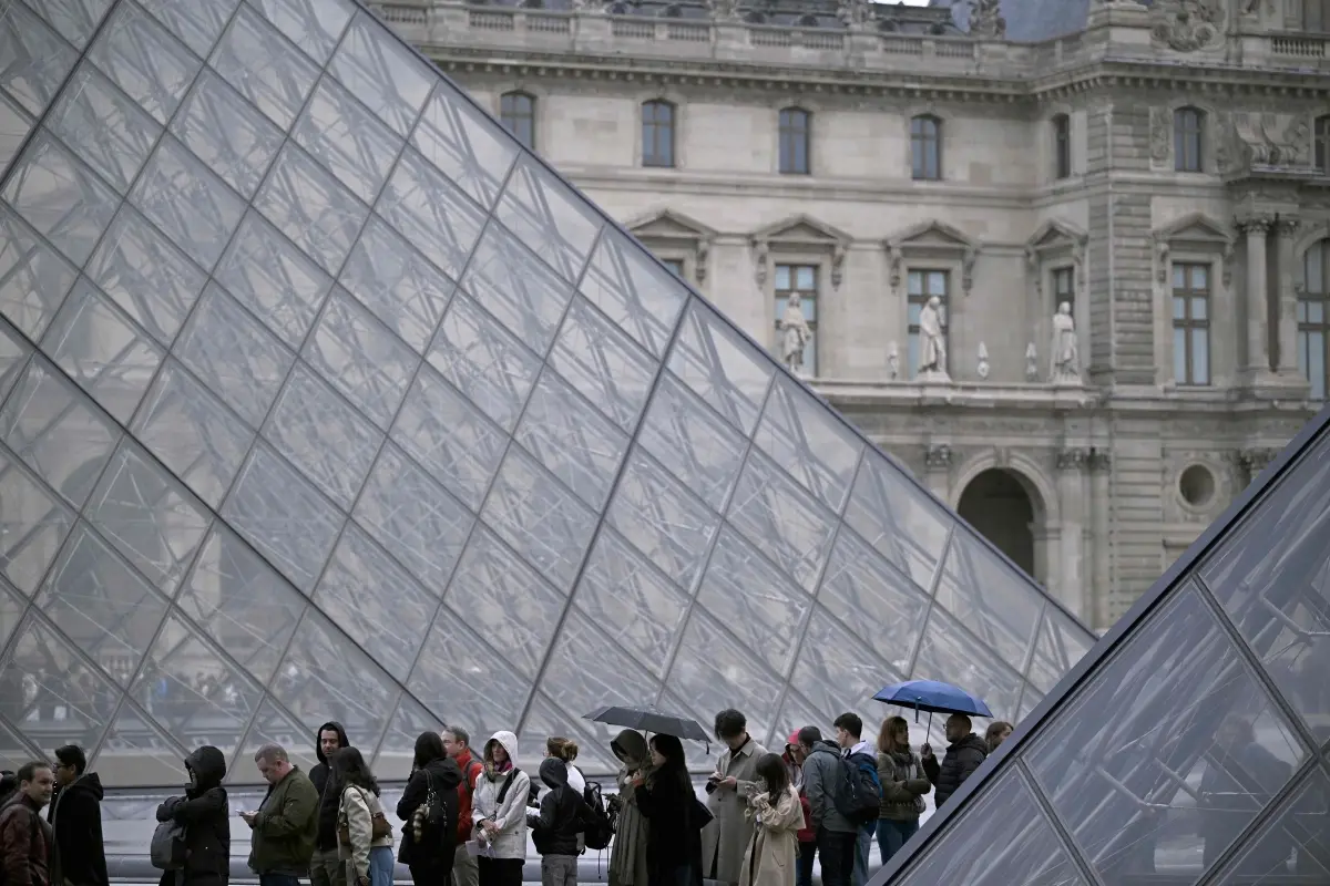 People queue in the Louvre pyramid courtyard moments before the announcement the museum will remain closed for a second day | Photo: AFP