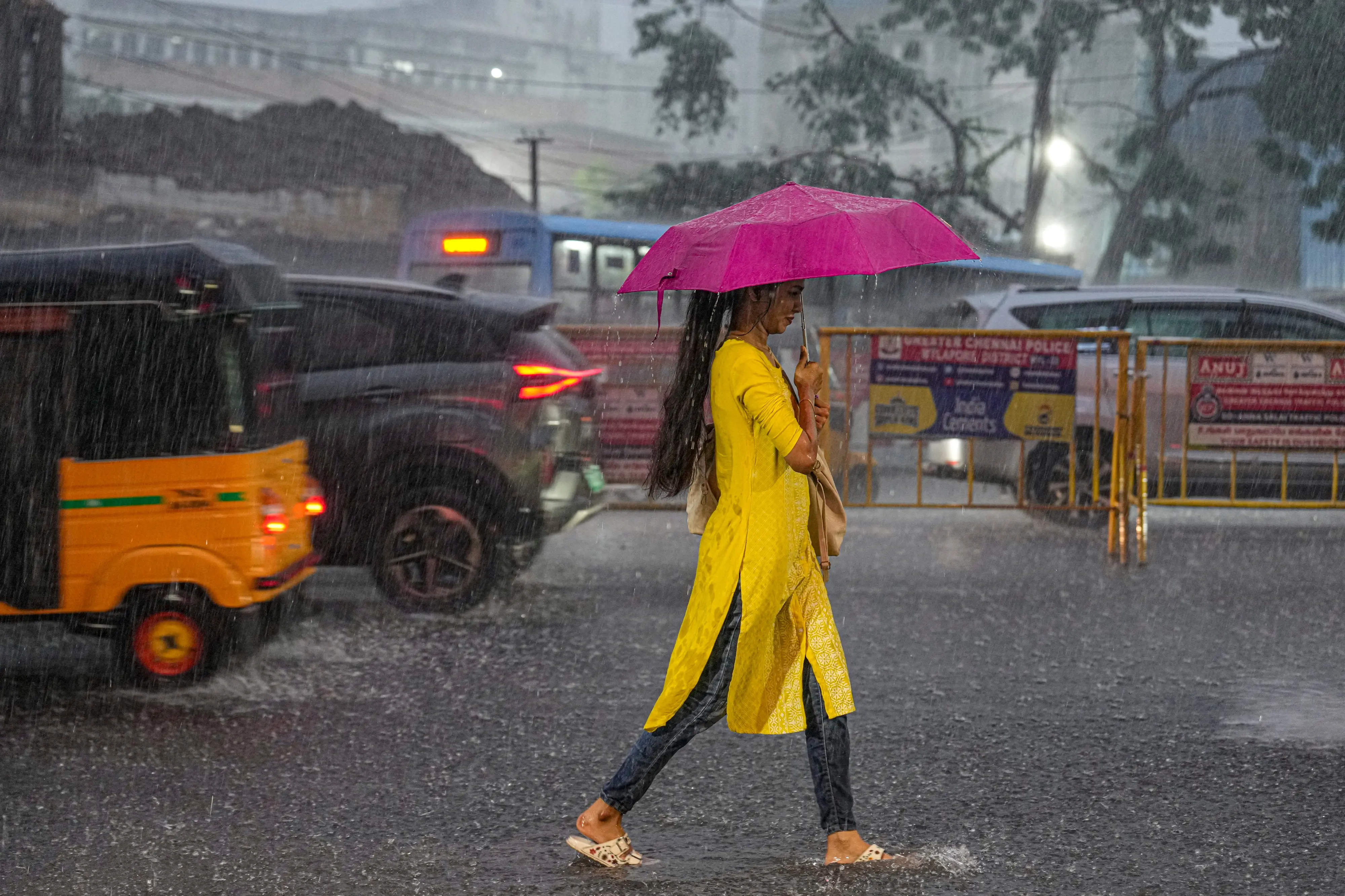 A woman walks with an umbrella on a road during heavy rainfall in Chennai | PTI