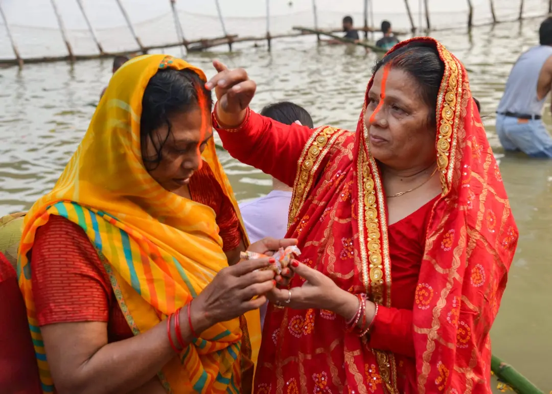 Devotees apply vermilion on each other on Kharna puja