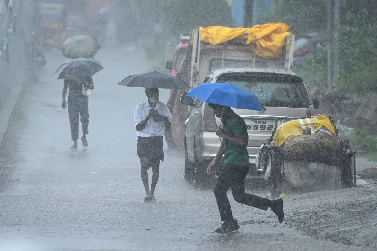 People holding umbrellas walk along a street amid heavy rains in Chennai on October 22, 2025 (Photo: AFP)