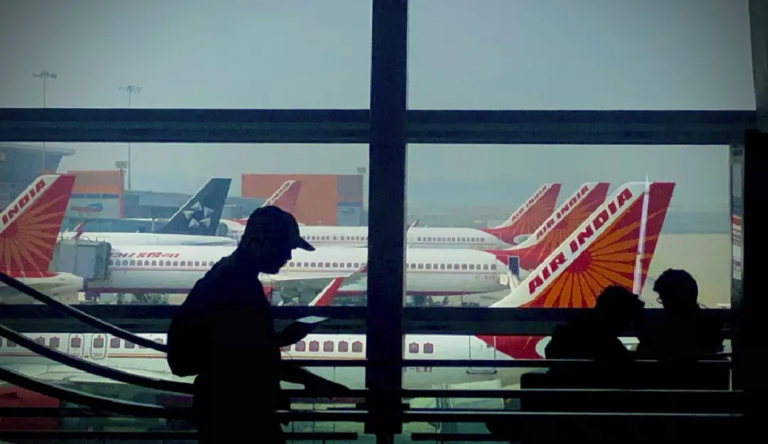 A man is silhouetted against an airport window with Air India aircrafts parked in the background in New Delhi | AP
