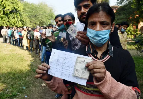 Voters show their voter ID cards while waiting in a queue to cast votes during the second phase of Uttar Pradesh Assembly elections, at a polling booth, in Moradabad on Monday. (ANI Photo)